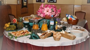 Una mesa de bufé con diversos alimentos, bebidas y un gran centro de flores.