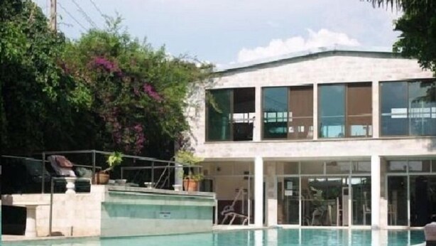 Un edificio moderno con piscina, ventanas amplias y una zona cubierta con asientos.
