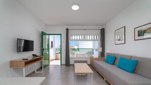 Ein modernes Wohnzimmer mit Sofa, Couchtisch, Fernseher und Schreibtisch.