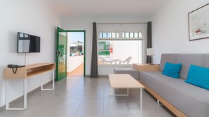 Ein modernes Wohnzimmer mit Sofa, Fernseher, Tisch und einer Bank.