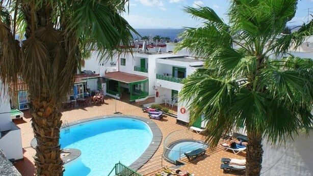 Ein Poolbereich mit Liegestühlen und Blick aufs Meer.