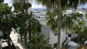 Ein Hotel mit Dachterrasse, Palmen und Meerblick.