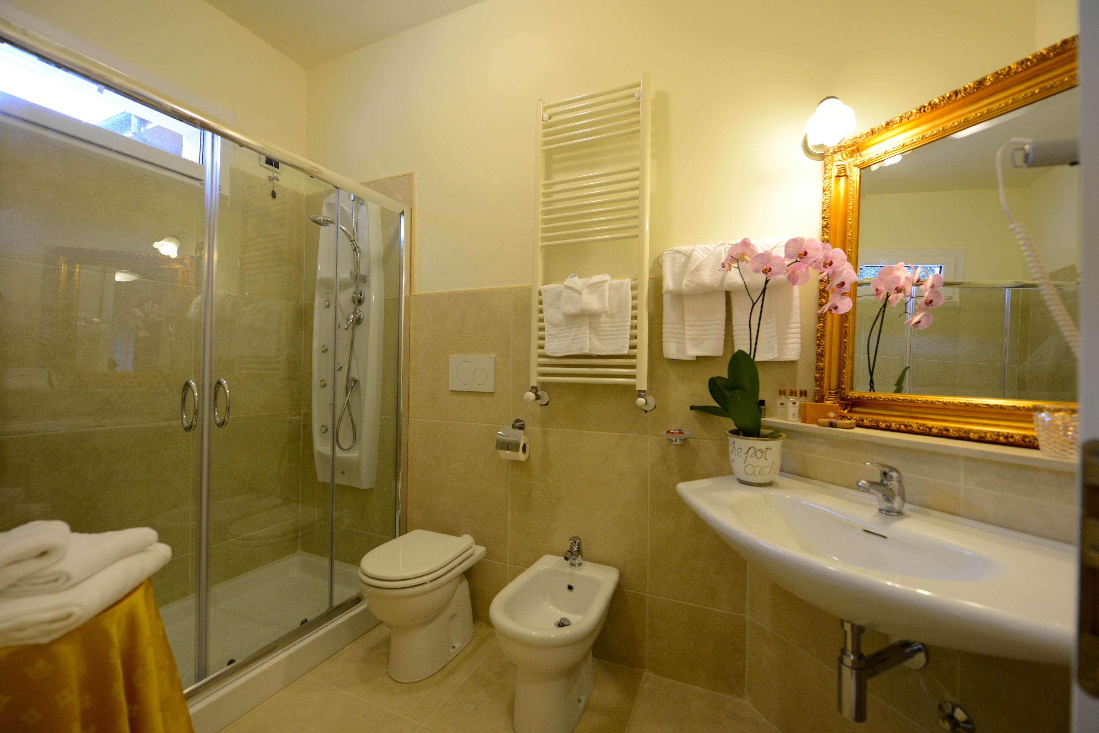 Ein Badezimmer mit einer Duschkabine, Toilette, Bidet und Waschbecken mit Spiegel.