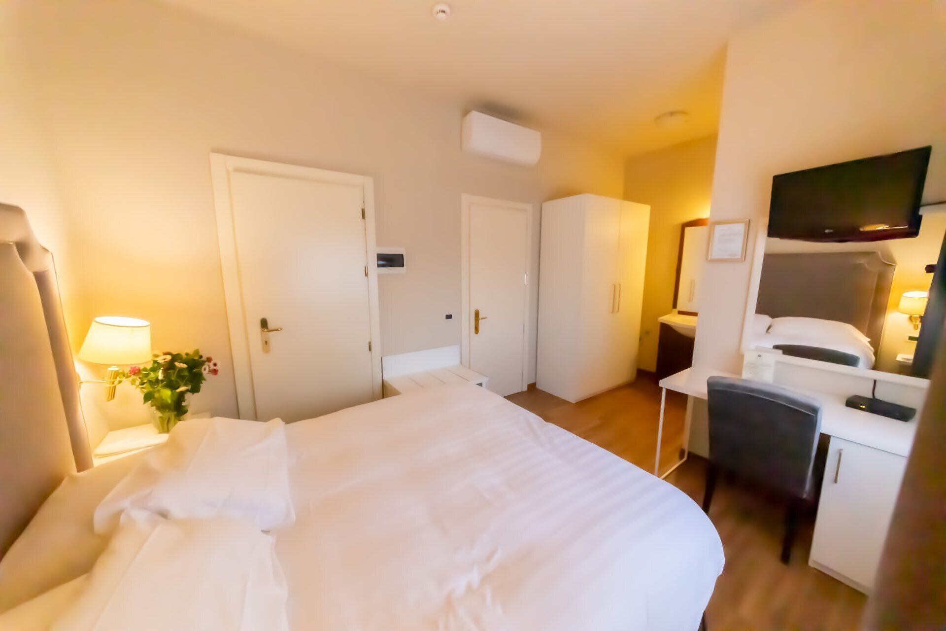 Una habitación de hotel con una cama, un escritorio, una silla, un televisor y una puerta.