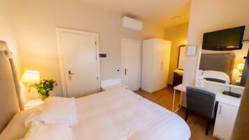 Una habitación de hotel con una cama, un escritorio, una silla, un televisor y una puerta.