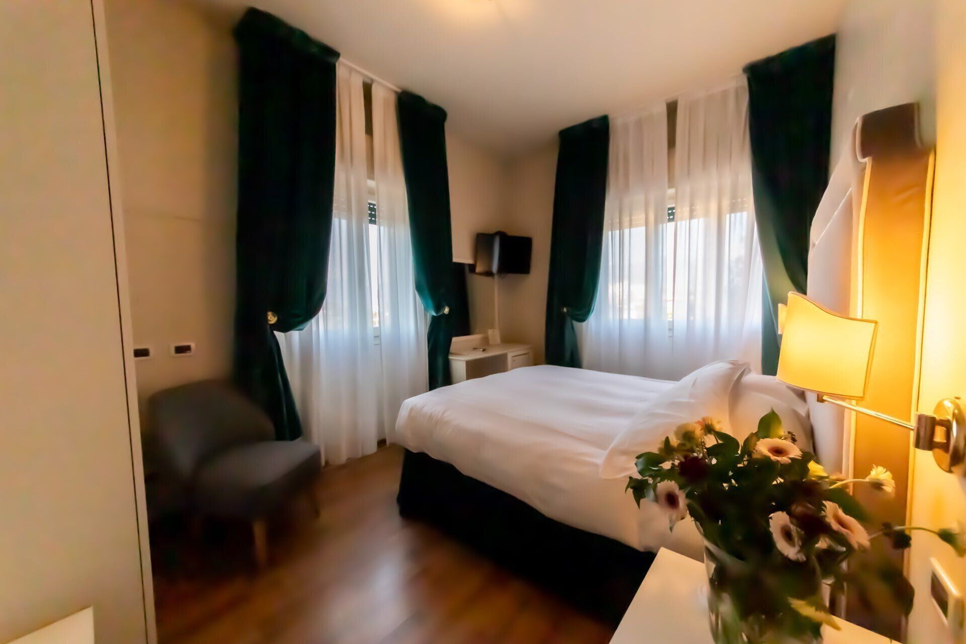 Ein Hotelzimmer mit einem Bett, einem Schreibtisch, einem Stuhl, einem Fernseher und einer Lampe.