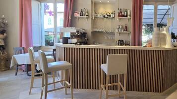 Uma área de bar com banquetas, balcão com garrafas e vista para o exterior.