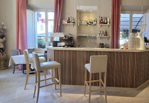 A bar area with stools, a counter with bottles, and a view of the outside. - Hotel Viscardo (Forte dei Marmi)