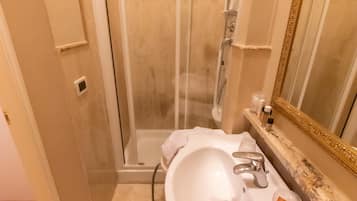 Ein Badezimmer mit Duschkabine, Waschbecken mit Spiegel und Handtuchhalter.