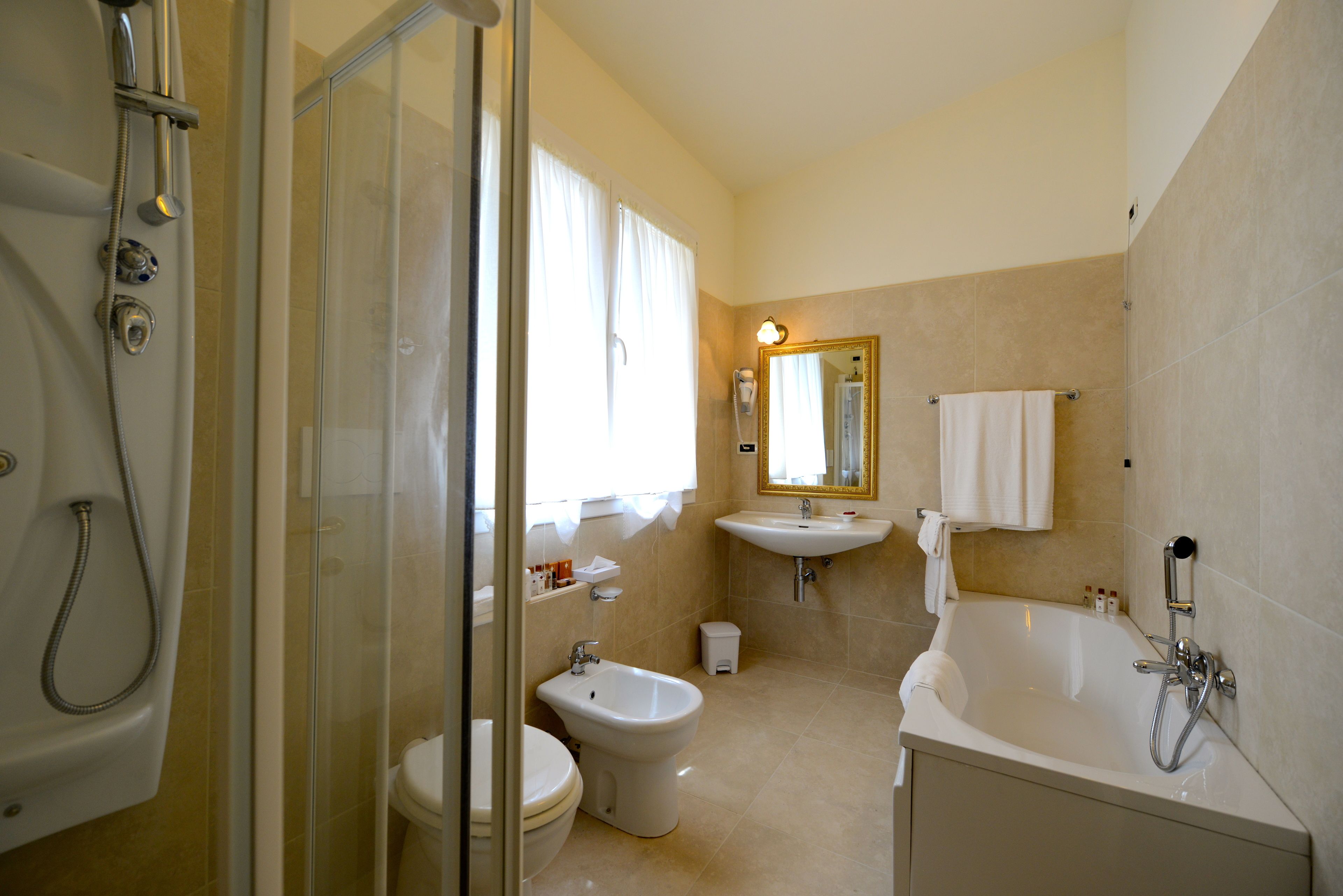Un bagno con doccia vetro, bidet, lavandino e vasca da bagno.