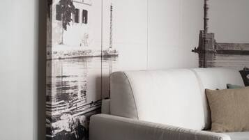 A modern living room with a sofa, a coffee table with a book and a cup, and a wall with large black-and-white photographs.