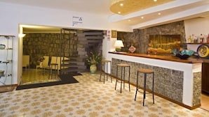 A bar area with a stone wall, bar stools, and a counter with a lamp.