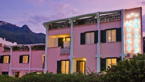 A pink building with balconies and a sign that reads "Hotel".