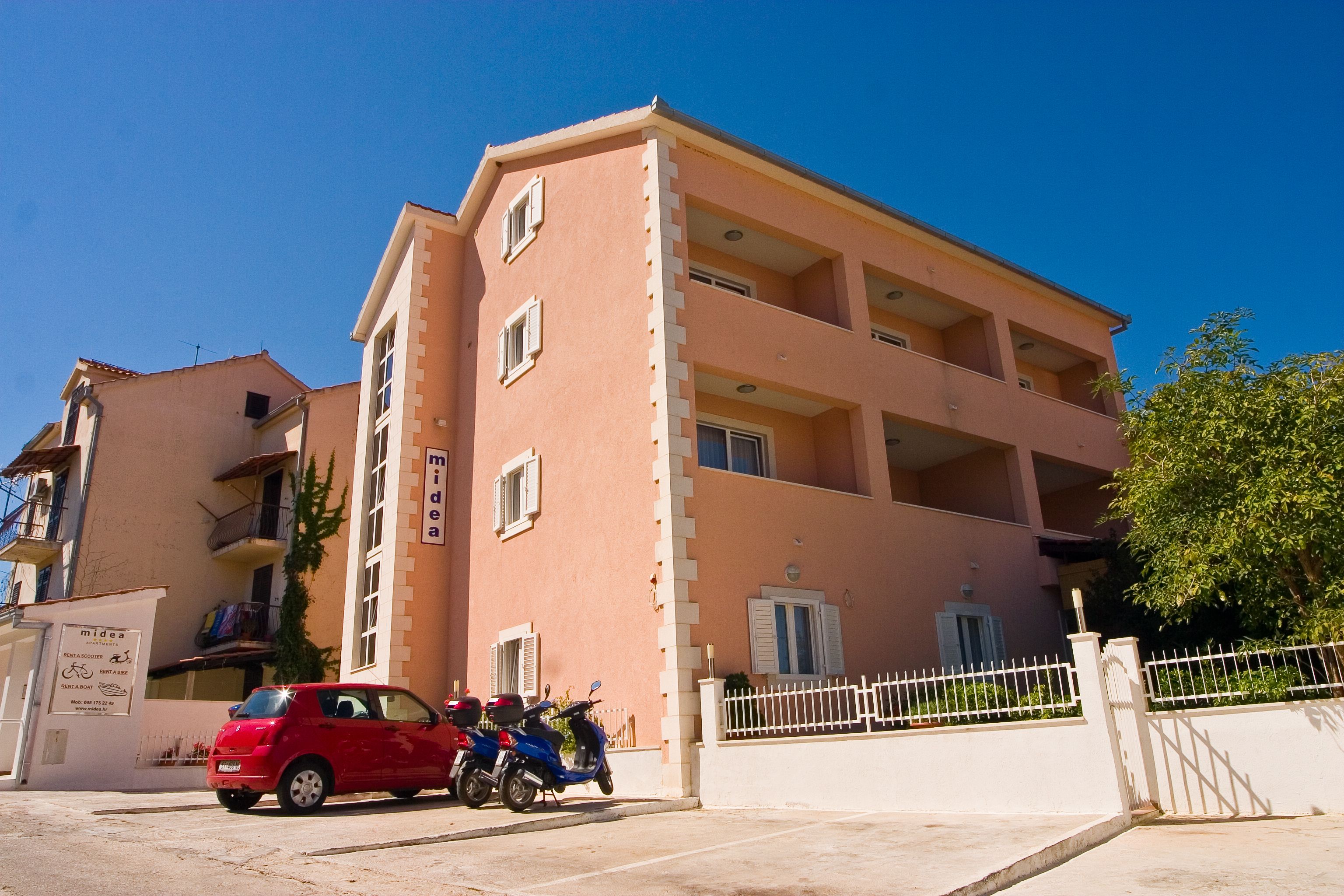 A multi-story building with a flat facade, balconies, and a gated entrance.