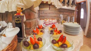 A buffet setup with various food items, including fruit bowls and a cake.
