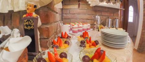 A buffet setup with various food items, including fruit bowls and a cake.