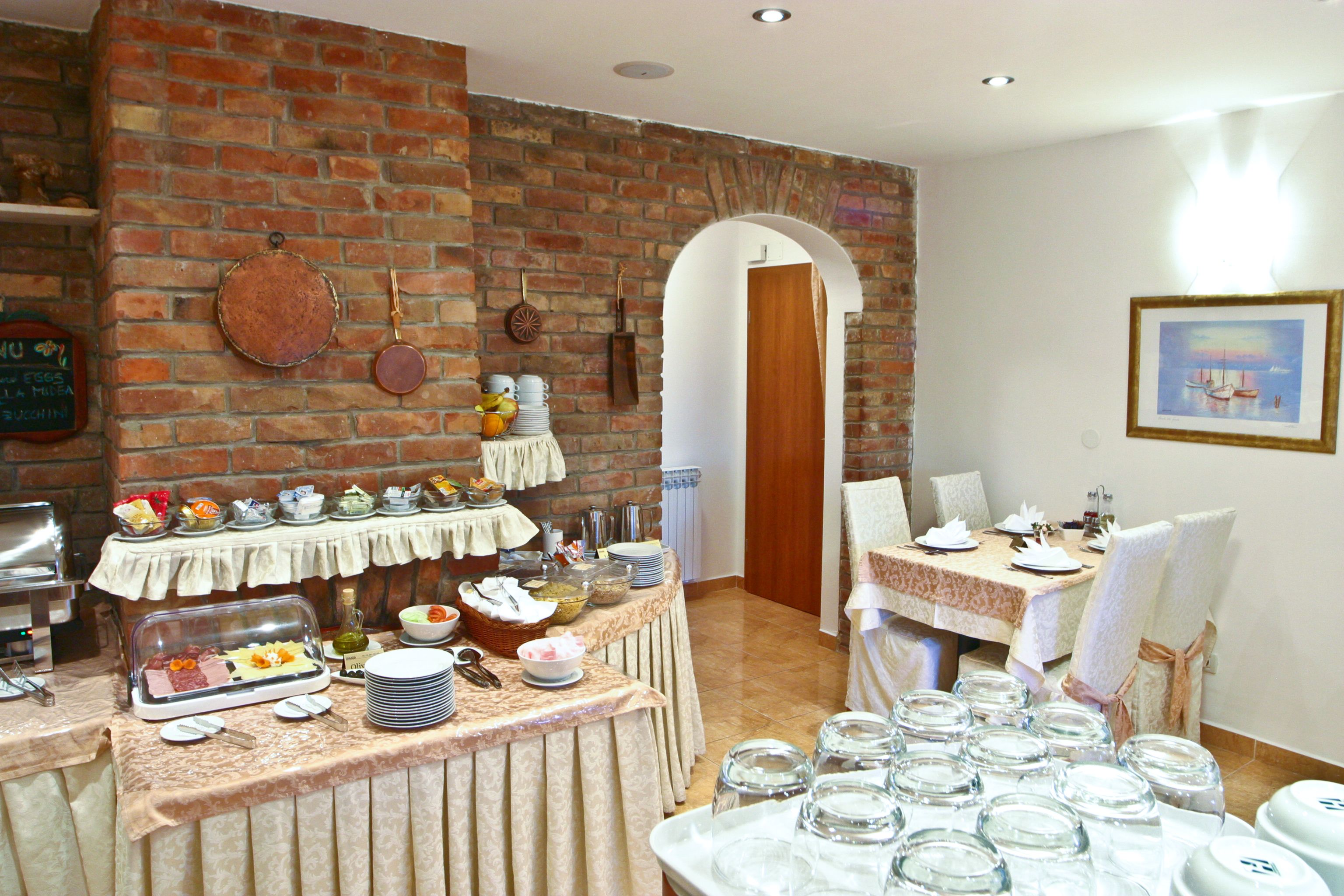 A dining area with a brick wall, a buffet table, and a dining table set for a meal.
