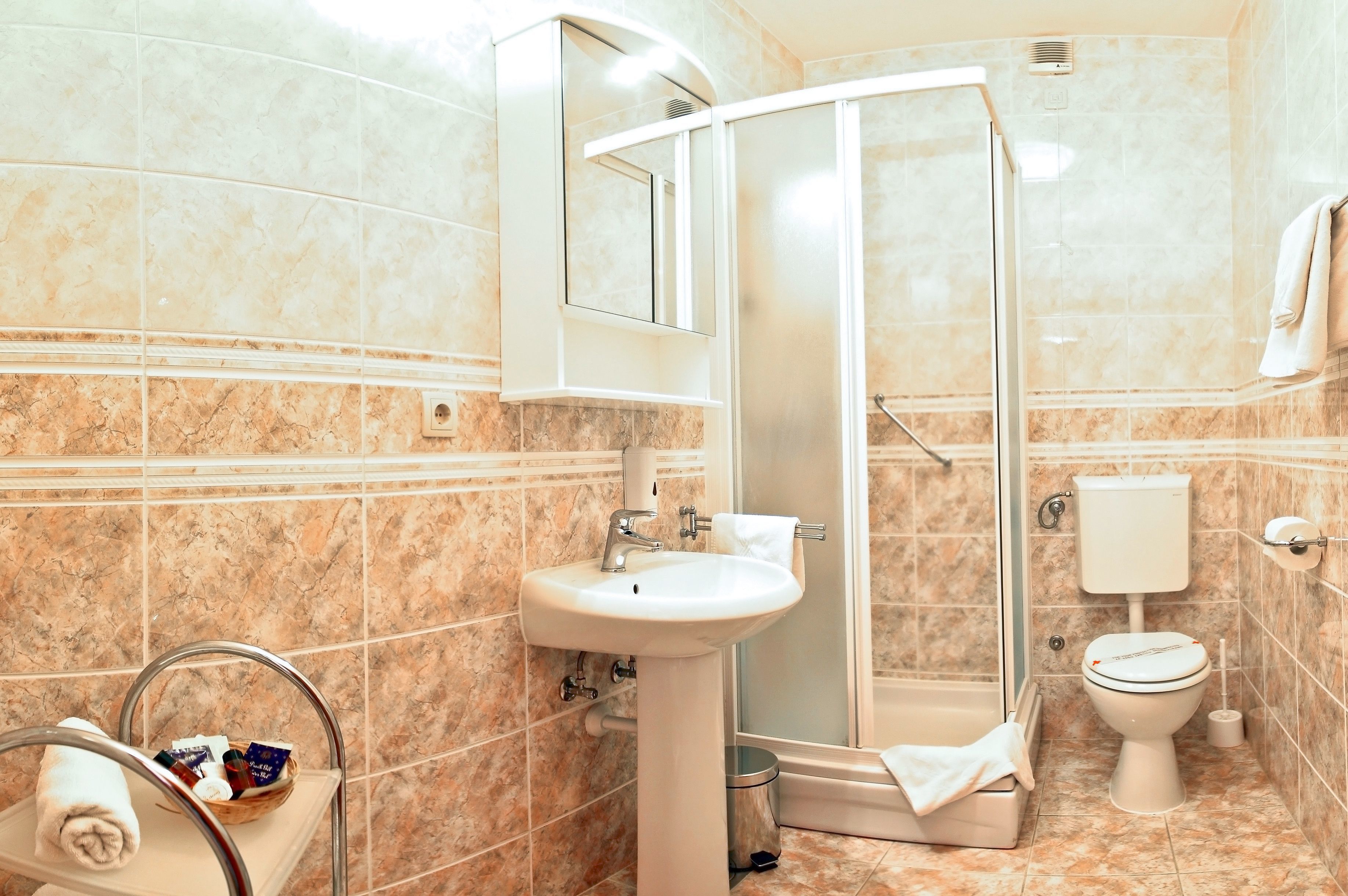 A bathroom with a sink, mirror, shower, toilet, and towel rack.