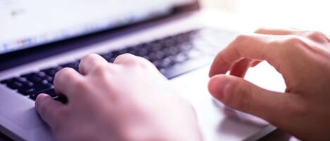 A close-up of hands typing on a laptop keyboard.