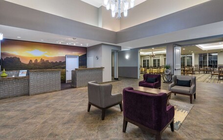 A spacious lobby with a reception desk, seating area, and a mural of a sunset.