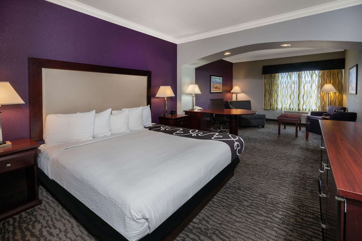 A hotel room with a large bed, a desk, a chair, and a small table.