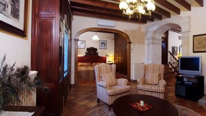 A cozy living room with striped armchairs, a television, a fireplace, and a peacock plant. - Recó de Randa (Algaida)