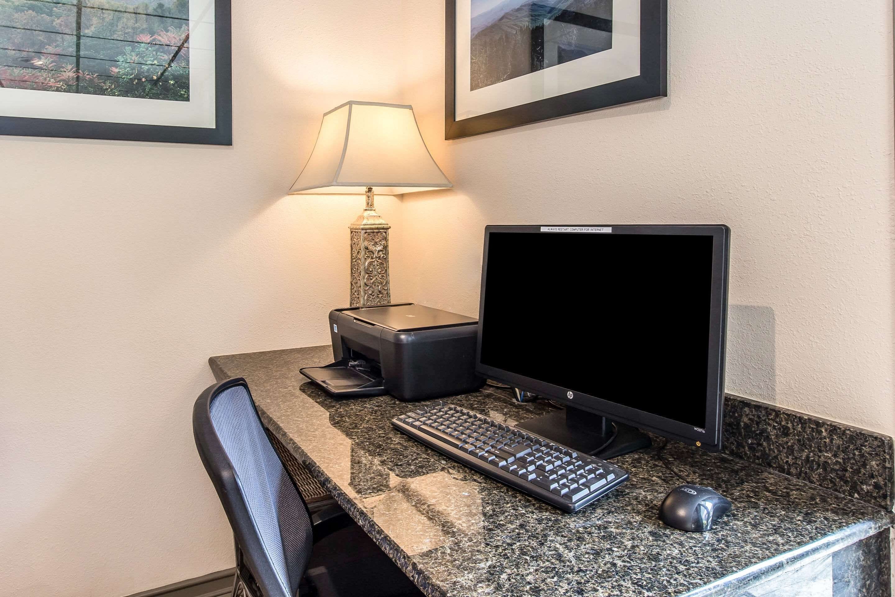 A workspace with a desktop computer, keyboard, mouse, and a printer on a granite countertop.
