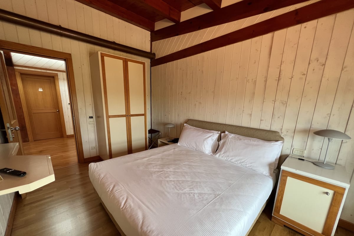A bedroom with a large bed, wooden headboard, bedside tables, and a wardrobe.
