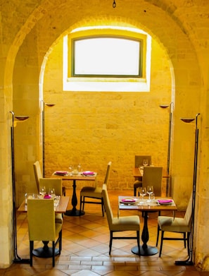 Een interieur met gewelfde plafonds, eettafels en een groot raam dat natuurlijk licht binnenlaat.