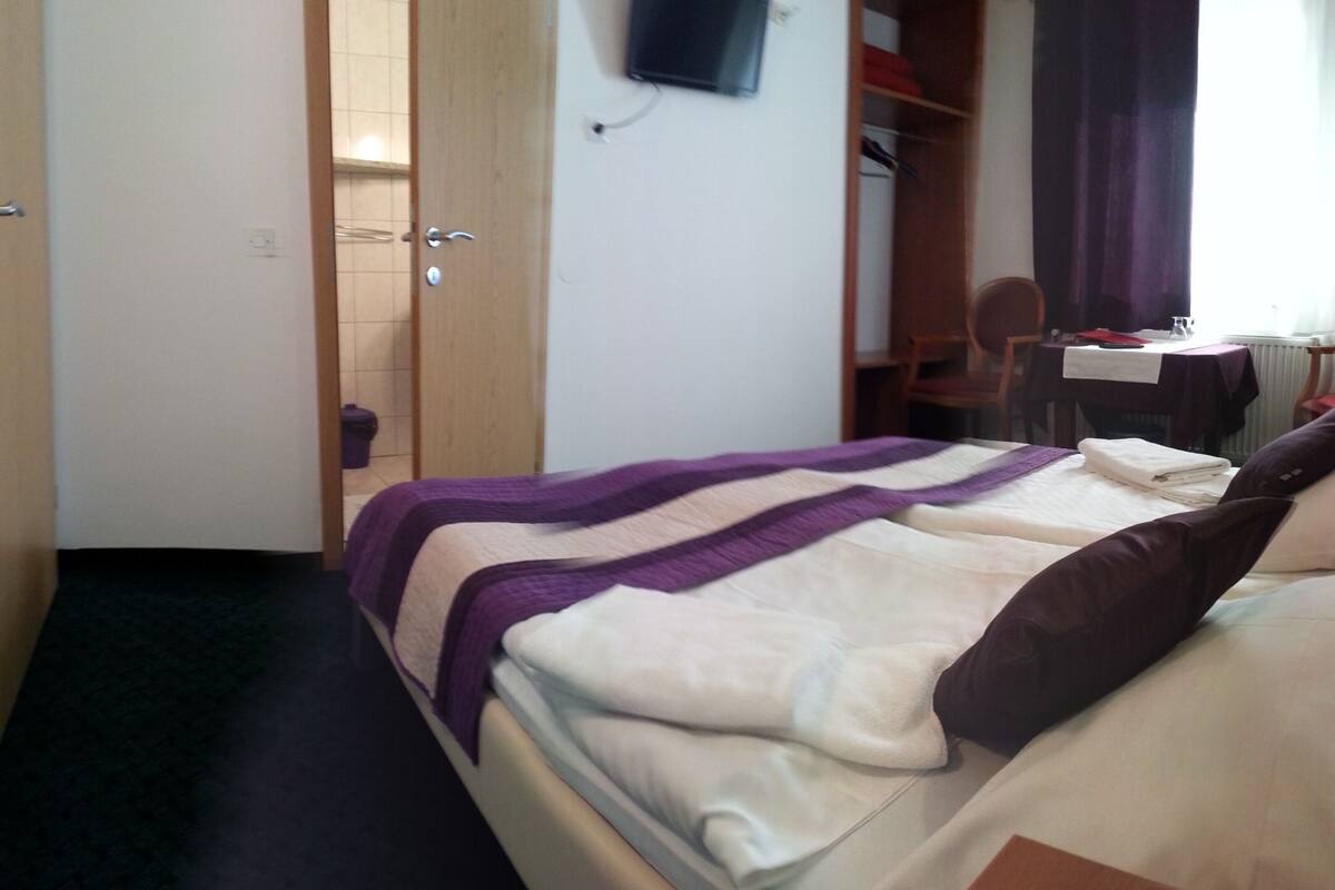 A hotel room with a bed, a desk, and a chair.