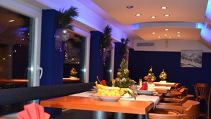 A restaurant with multiple tables and chairs, decorated with Christmas trees and a fruit bowl. - Hotel Silvester (Cerklje na Gorenjskem)