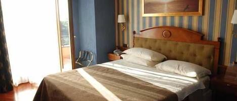 Une chambre d’hôtel avec un grand lit, une table de chevet, une lampe et un tableau au mur.
