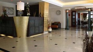 Een moderne hotellobby met een receptiebalie, een zithoek en een gepolijste vloer.