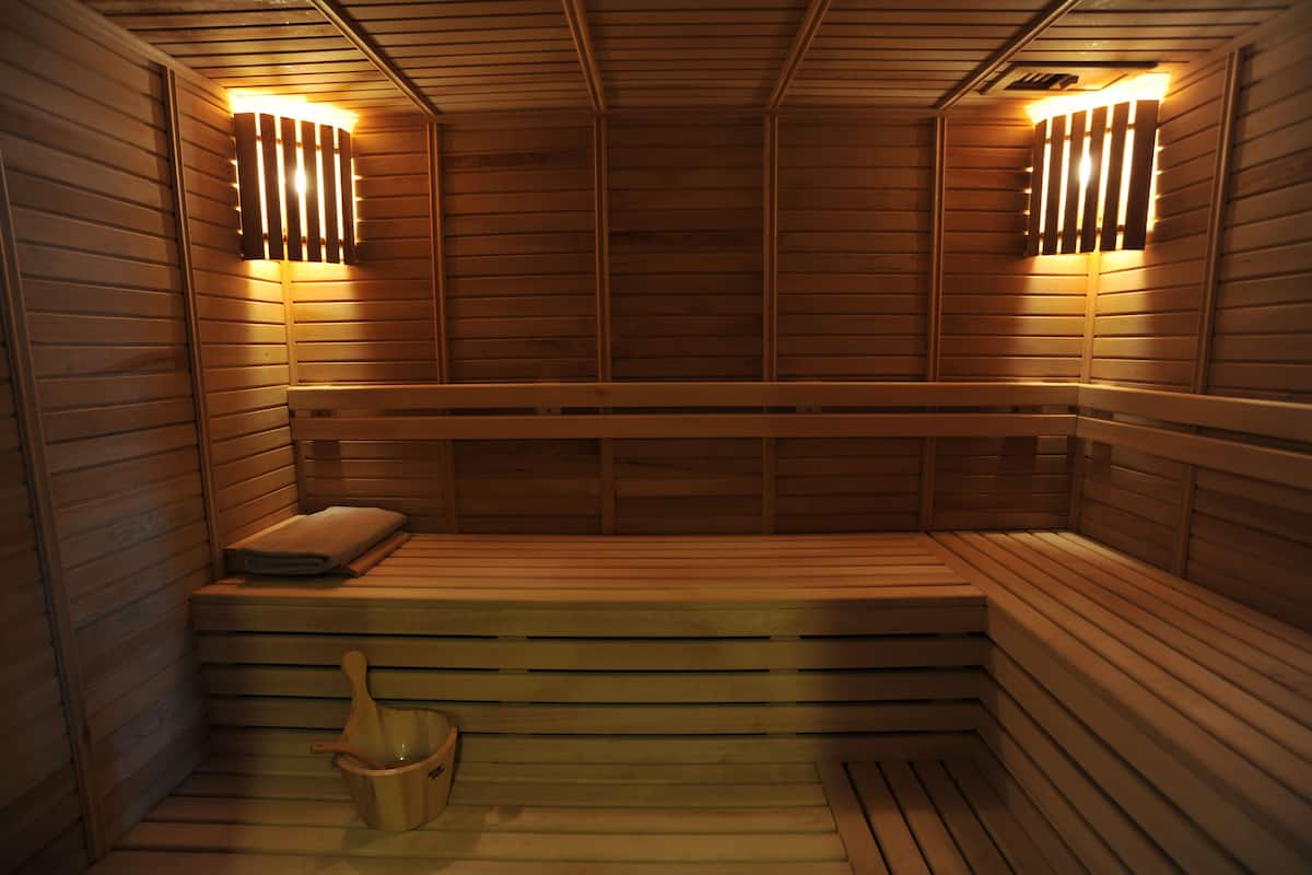 Relax in a serene sauna with a U-shaped seating area and a wooden bucket at your disposal.