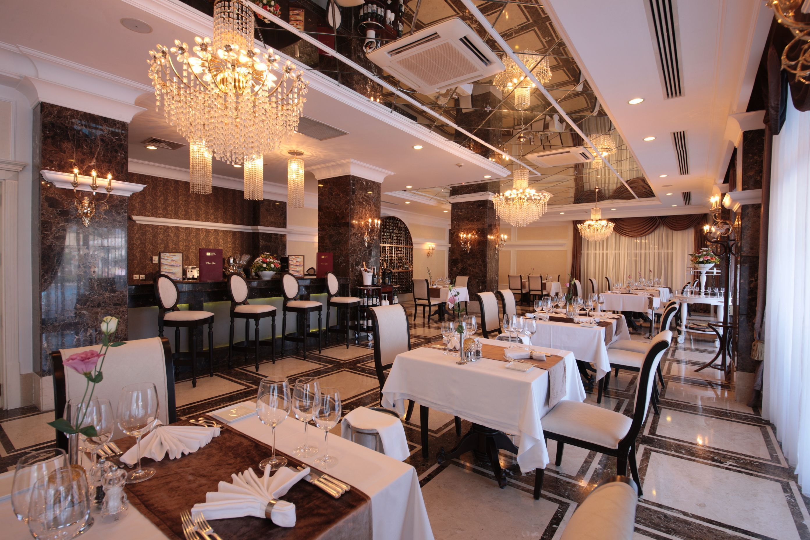 Ein Restaurant mit mehreren Speisetischen, Kronleuchtern und Marmorböden.