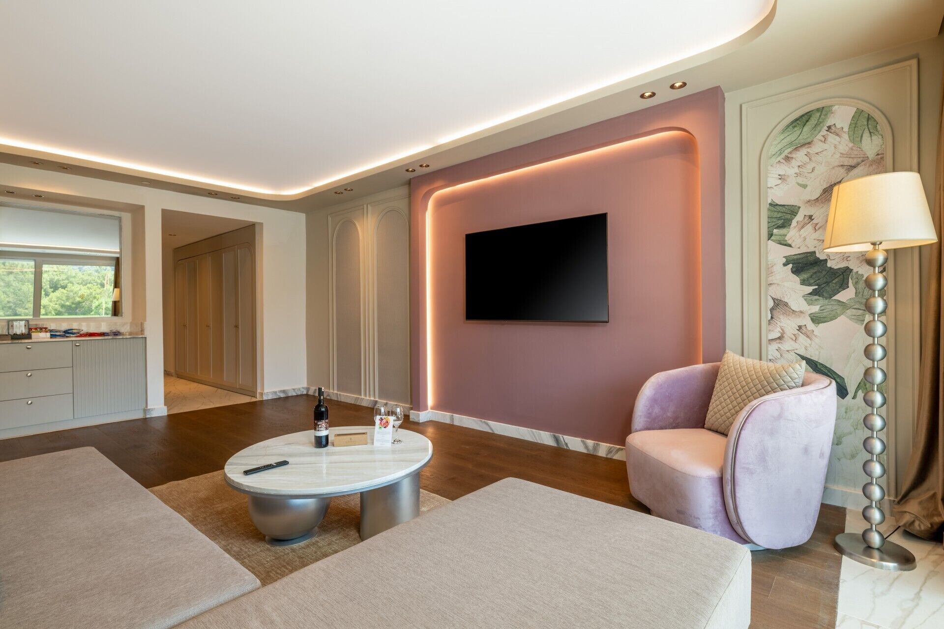 A modern living room with a round coffee table, a comfortable armchair, and a flat-screen TV mounted on the wall.