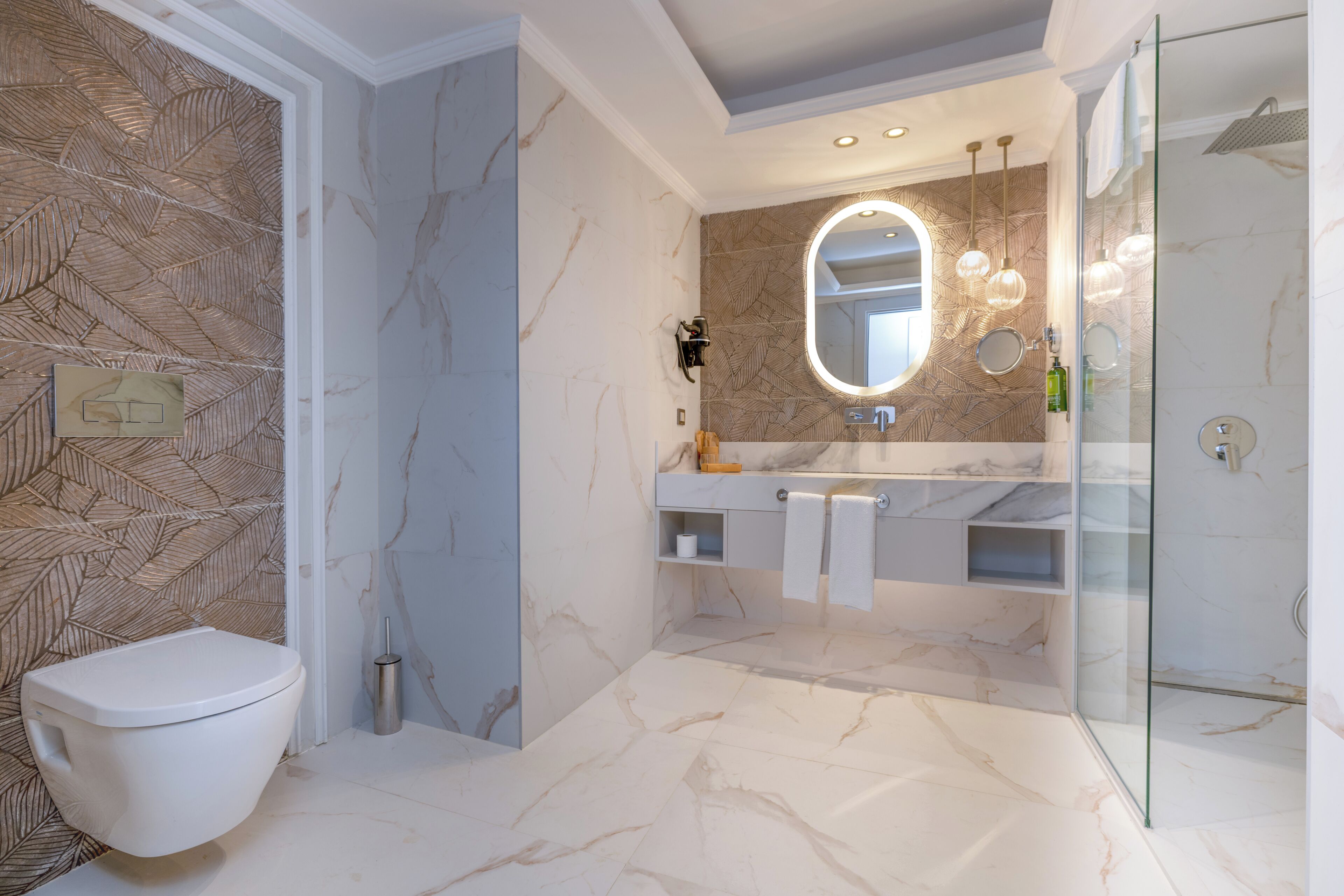 A modern bathroom with a toilet, a glass shower enclosure, a vanity with a mirror, and a marble floor.