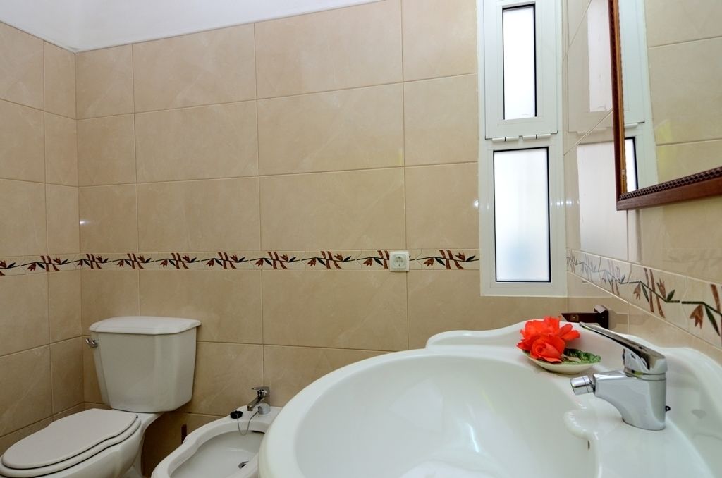 A bathroom with a toilet, sink, and mirror.