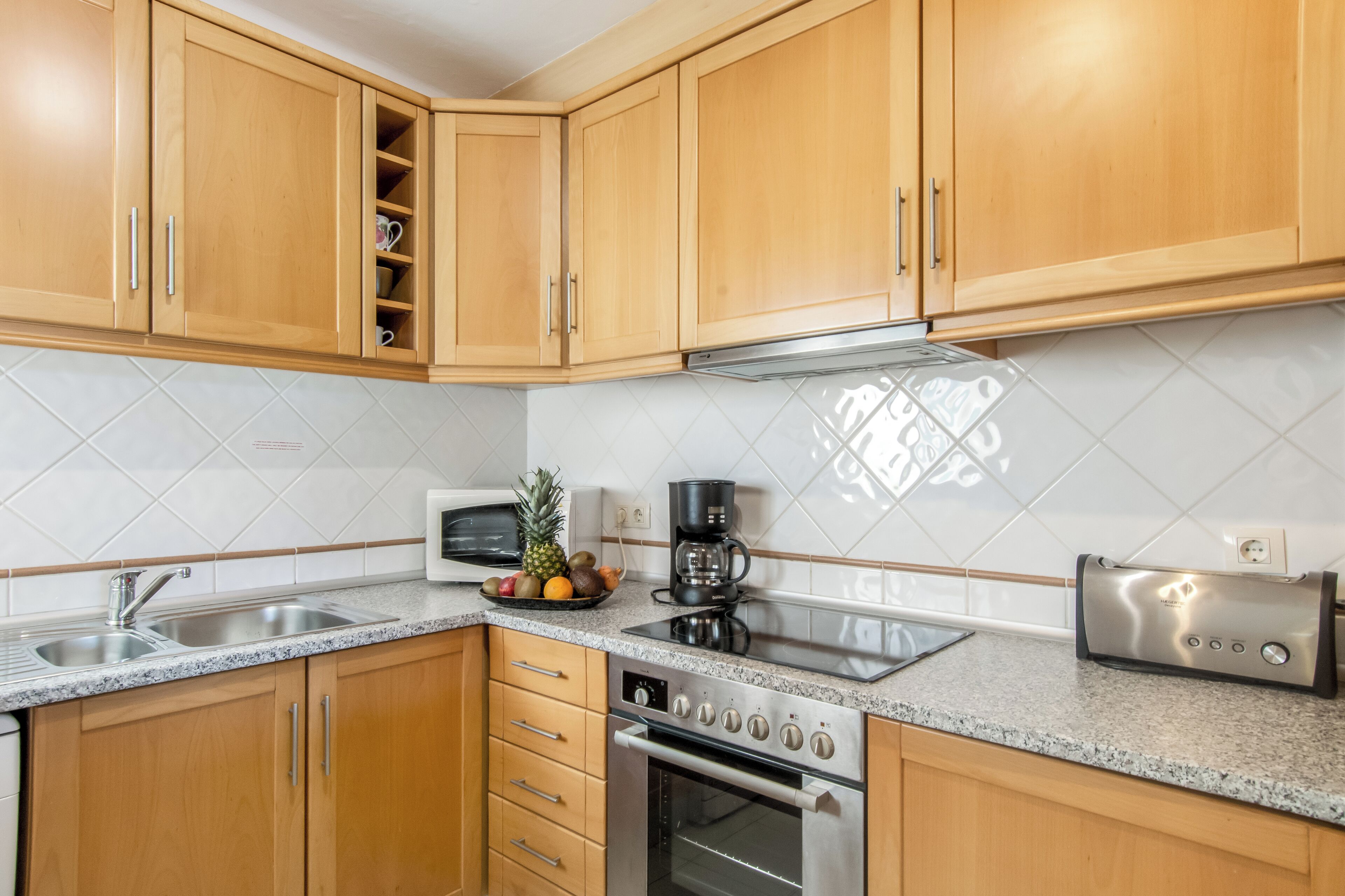 A kitchen with wooden cabinets, a stainless steel stove, a microwave, and a toaster.