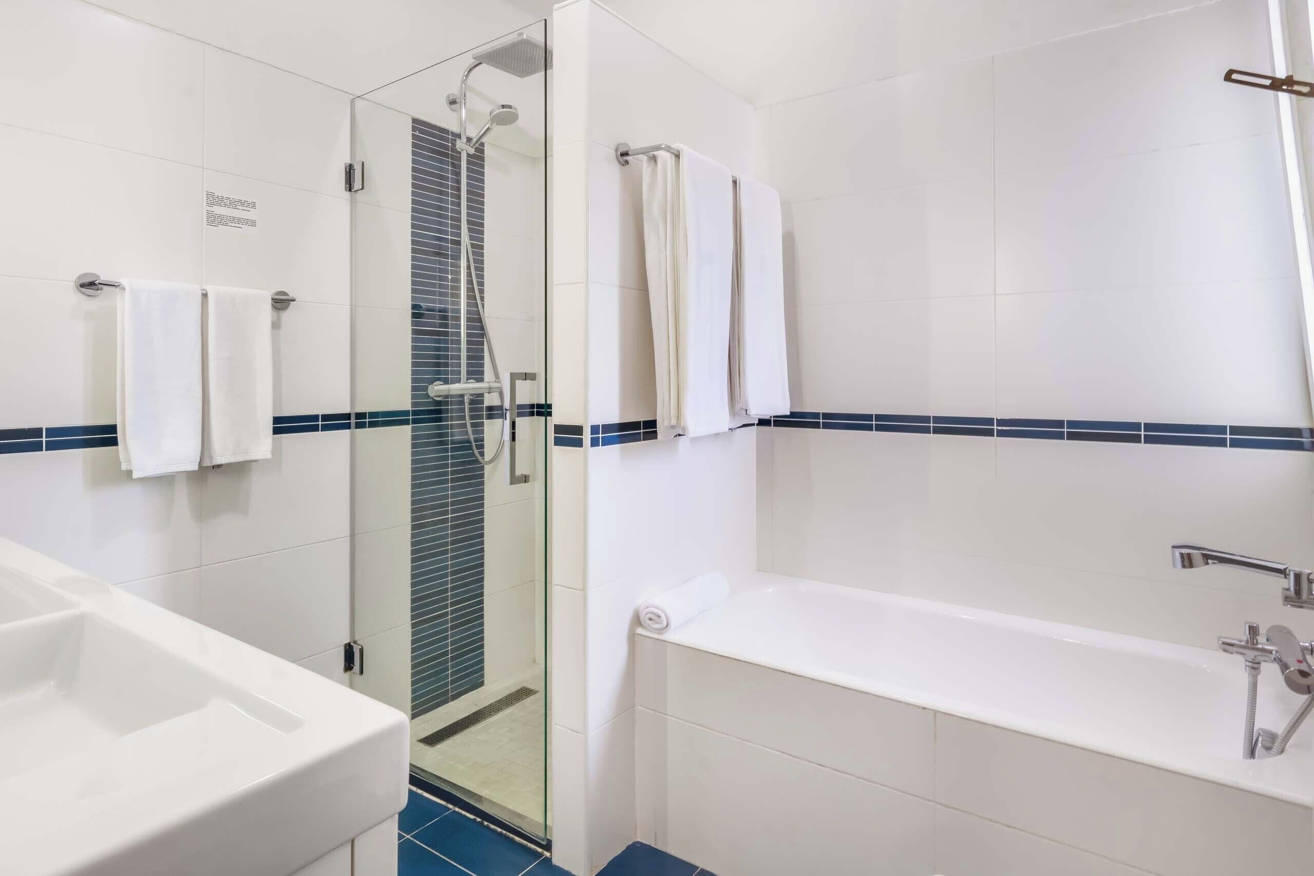 A modern bathroom with a glass-enclosed shower, a white bathtub, and a sink.