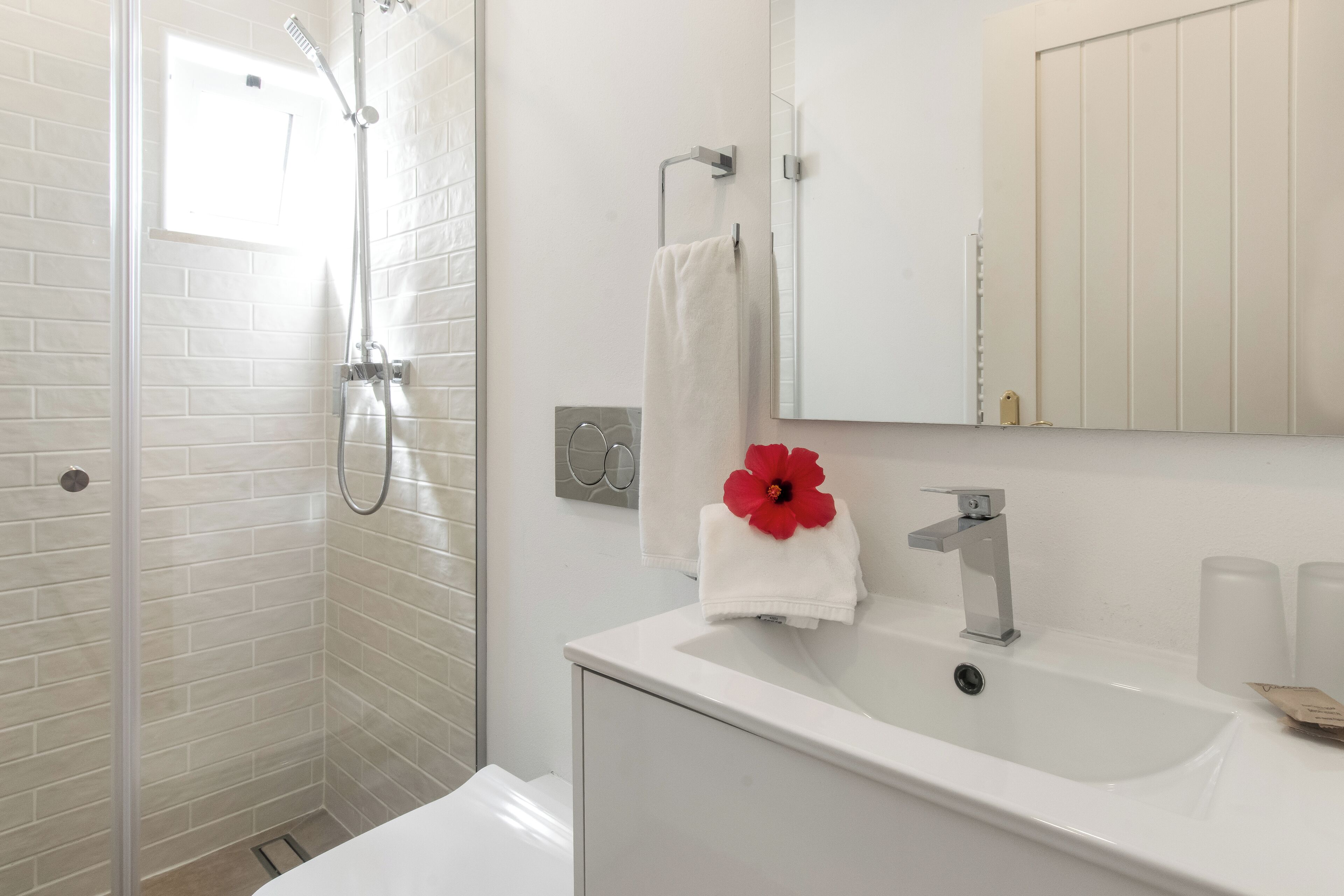 Un baño moderno con cabina de ducha de vidrio, un lavabo blanco y un espejo sobre él.
