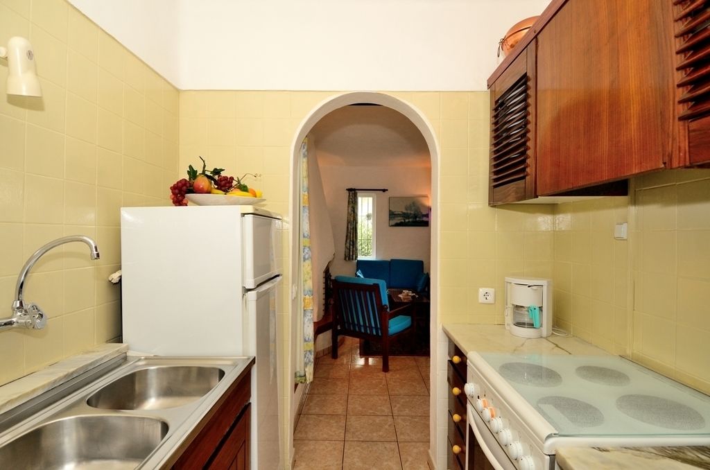 A compact kitchen with a white refrigerator, double sink, and a stove.