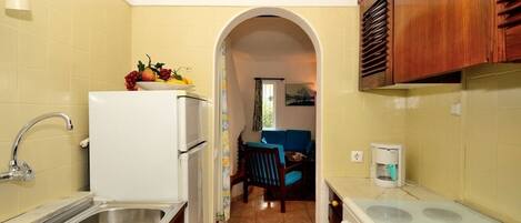 A compact kitchen with a white refrigerator, double sink, and a stove.