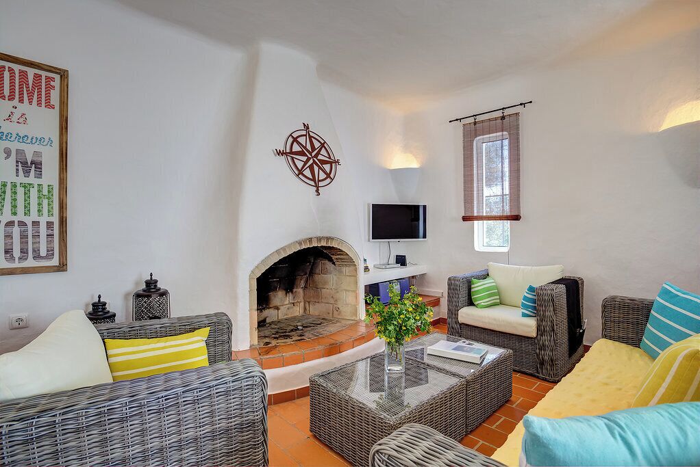 A cozy living room with wicker furniture, a fireplace, a flat-screen TV, and a wall-mounted compass.