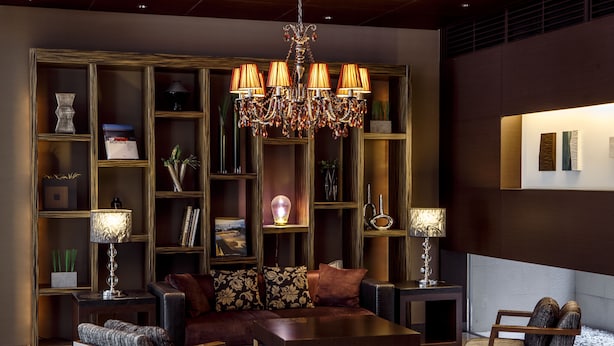 Een moderne woonkamer met een donker houten boekenkast, een kroonluchter en een zithoek.