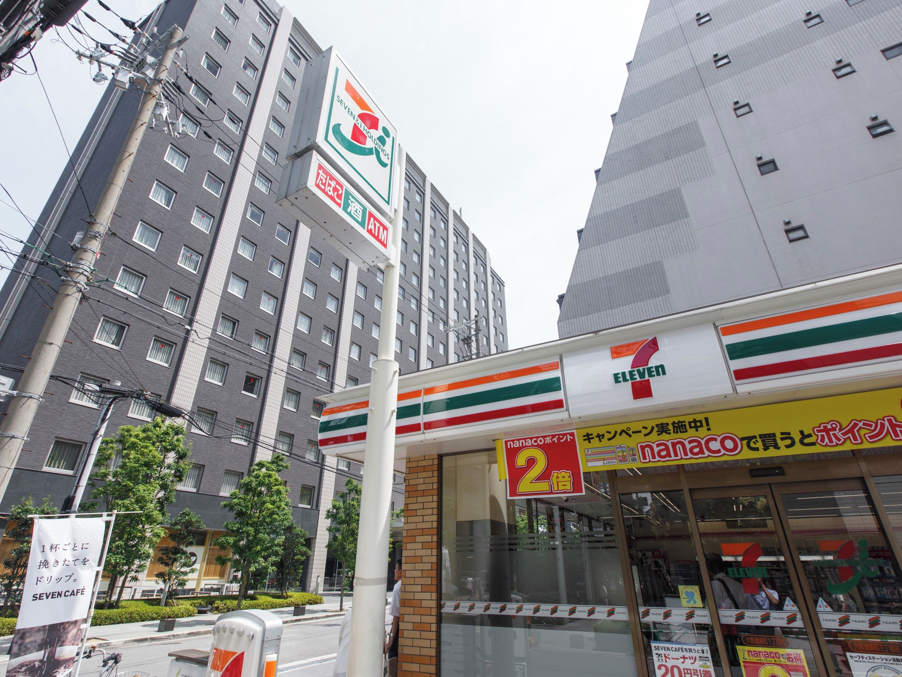 Ein 7-Eleven-Convenience-Store mit auffälliger Beschilderung in einem Stadtgebiet mit hohen Gebäuden.