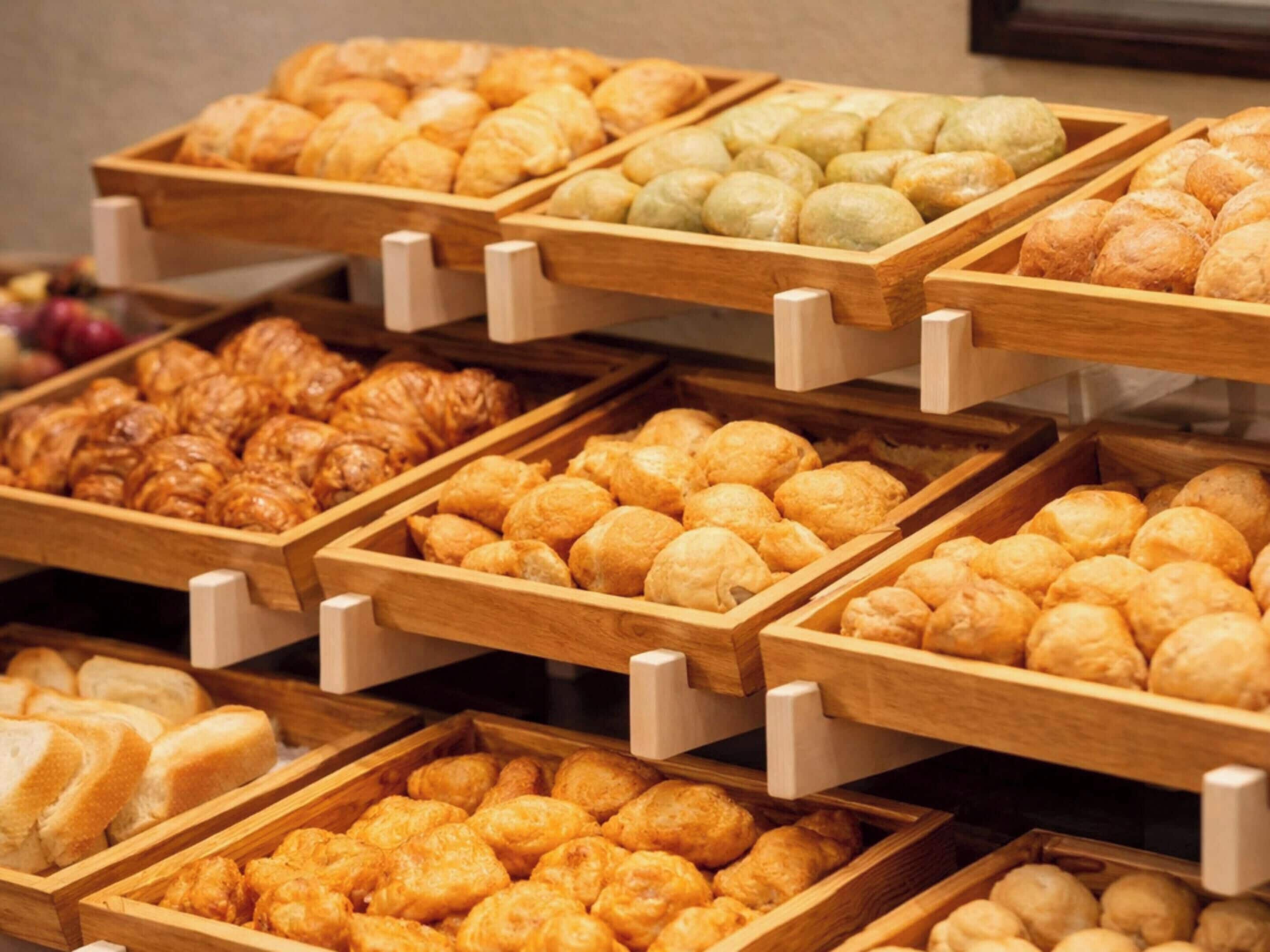 Una vitrina de panadería con diversos productos horneados en bandejas de madera.