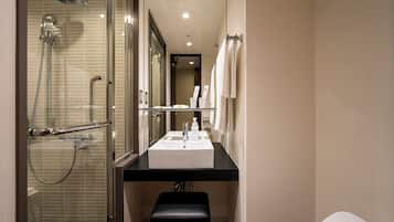 Une salle de bain moderne avec une douche à parois de verre, un lavabo blanc et un banc.