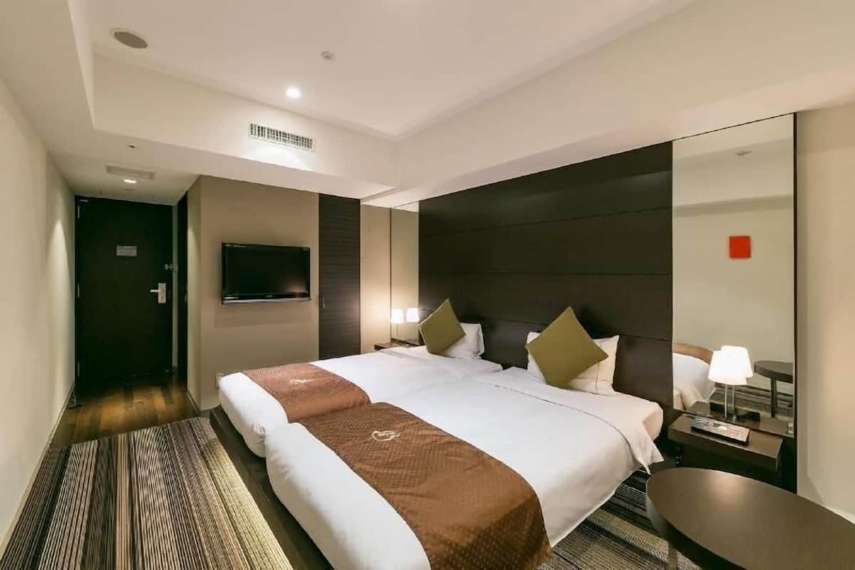 Een hotelkamer met een groot bed, een flatscreen televisie, een nachtkastje met lamp en een spiegel.