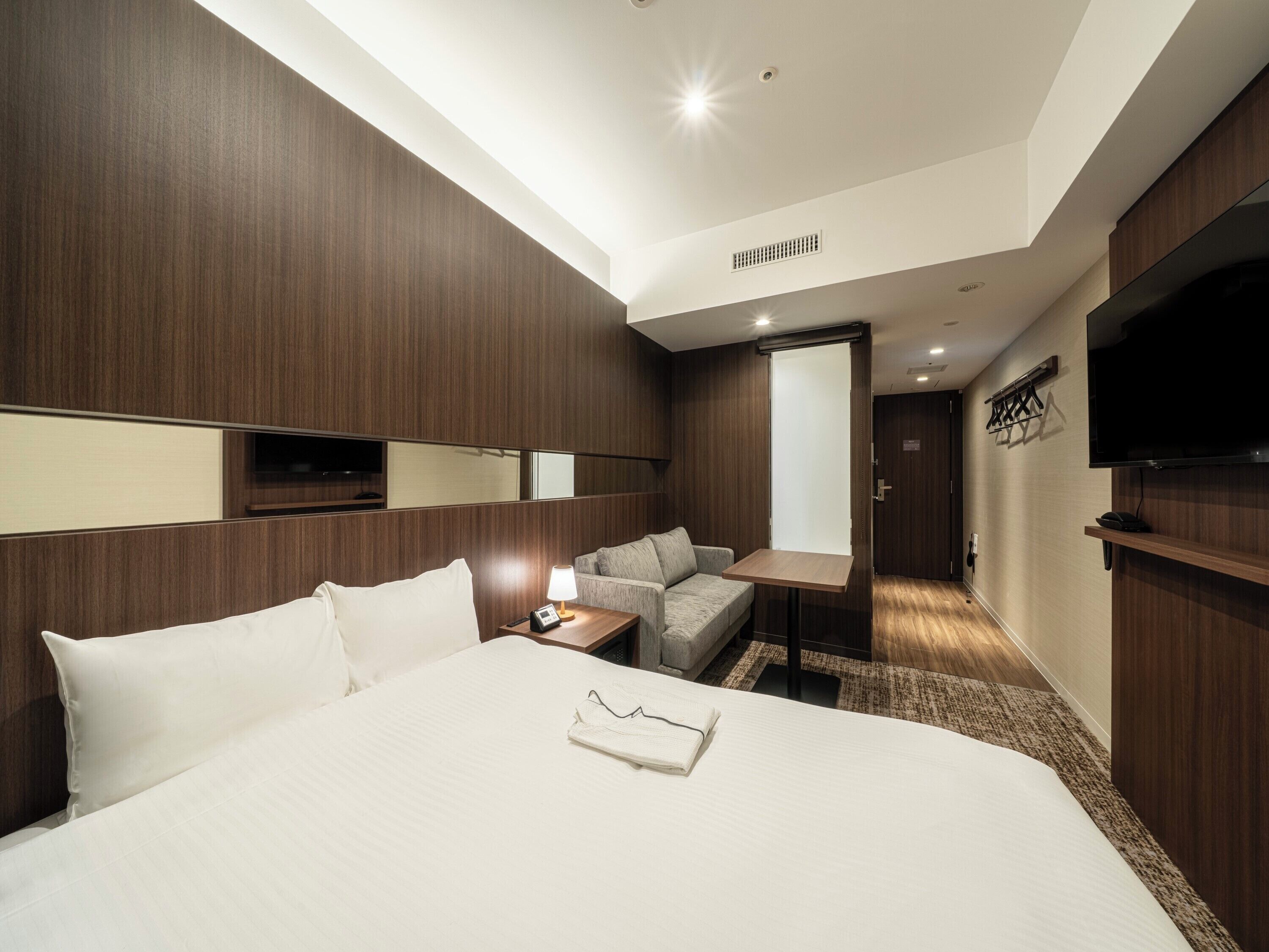 Une chambre d’hôtel avec un grand lit, un canapé, une télévision et un miroir.